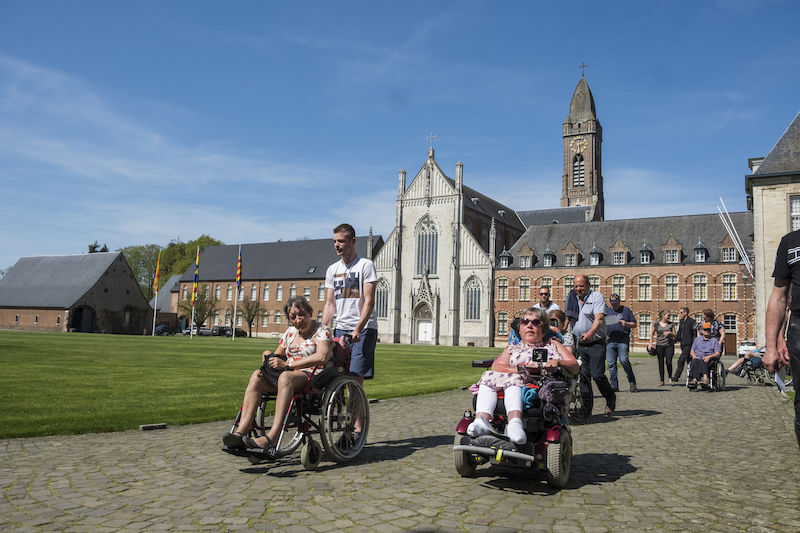Mensen met een motorische beperking wandelen op het binnenplein van de abdij van Tongerlo
